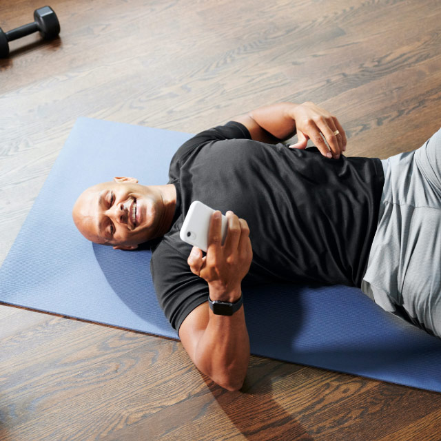 Man smiling while resting on his mat during an at-home virtual training workout session