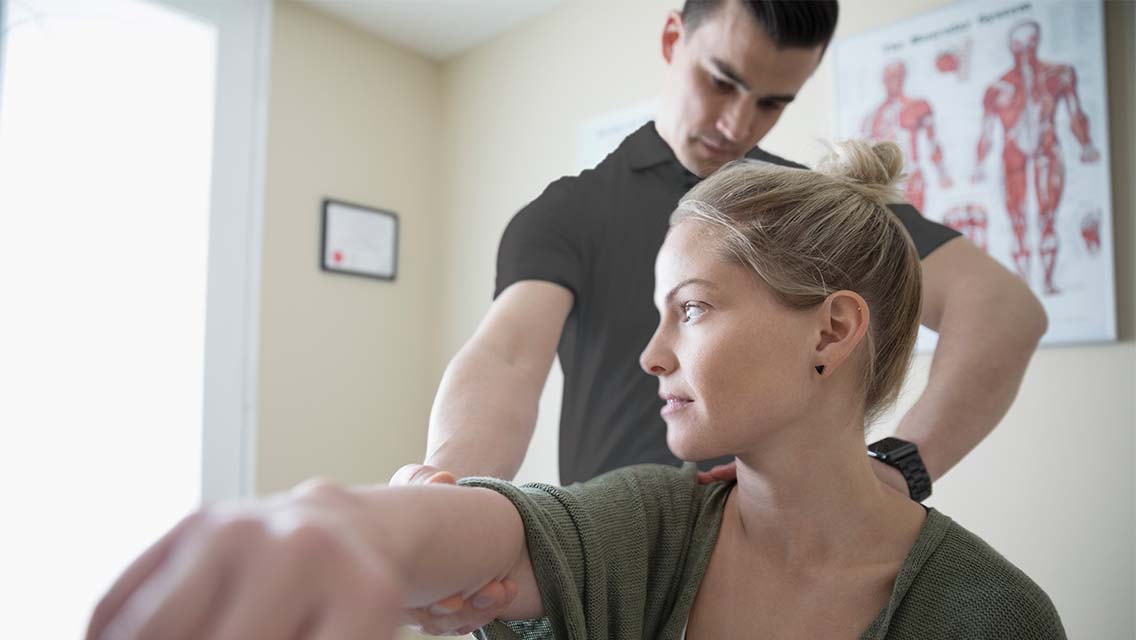 A physical therapist holding the arm of a client who is sitting