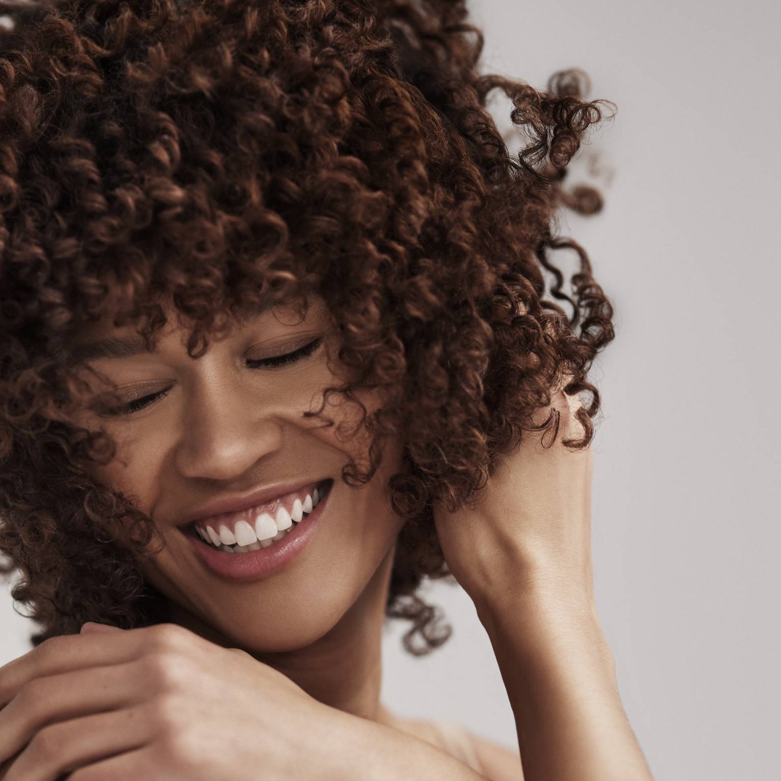 A woman smiling and playing with her hair