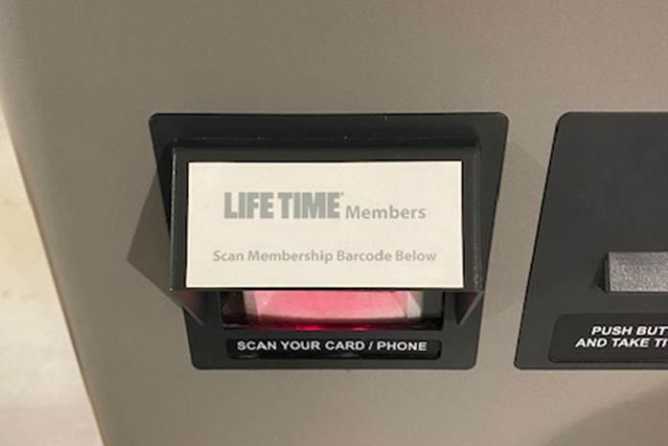 A parking terminal at Life Time Coral Gables with a red circle around a slot labeled “Athletic members scan card below”