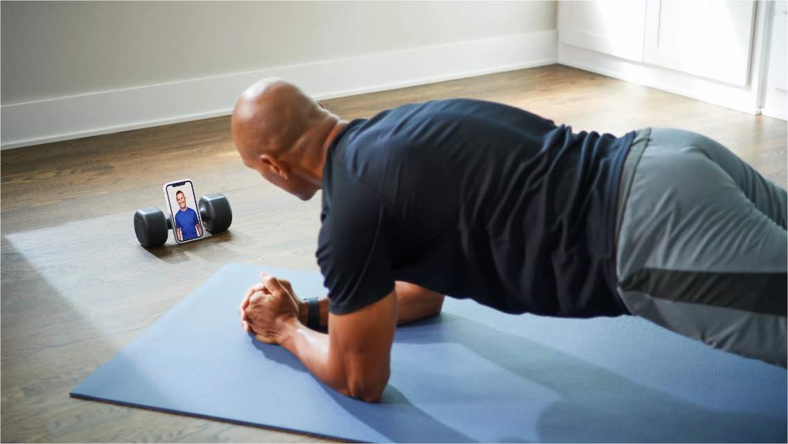 Man doing a plank while talking to a personal trainer using the Life Time app.