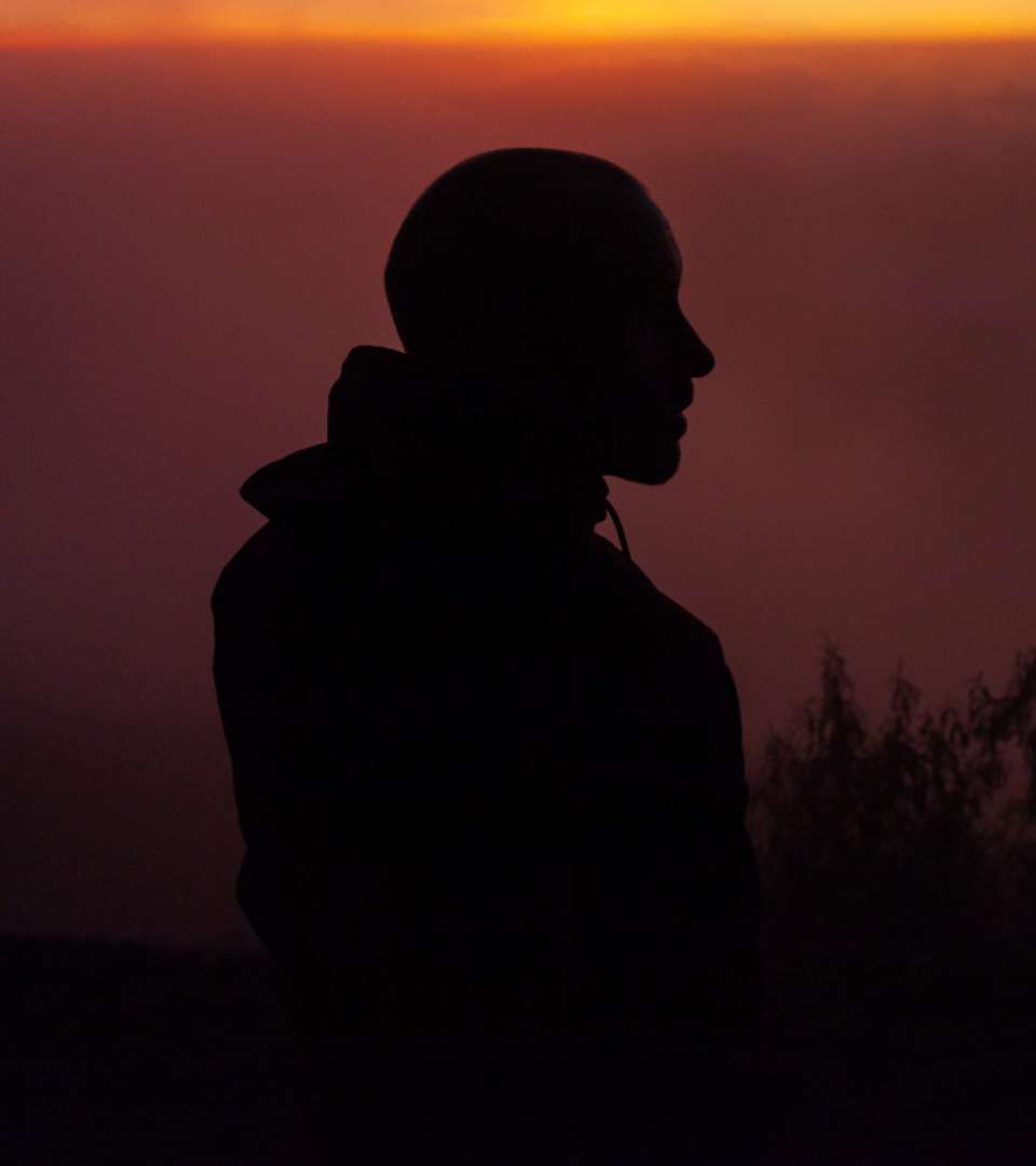 a silhouette of a man with the sunset