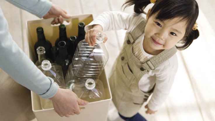 Small child placing a plastic bottle in the recycling.