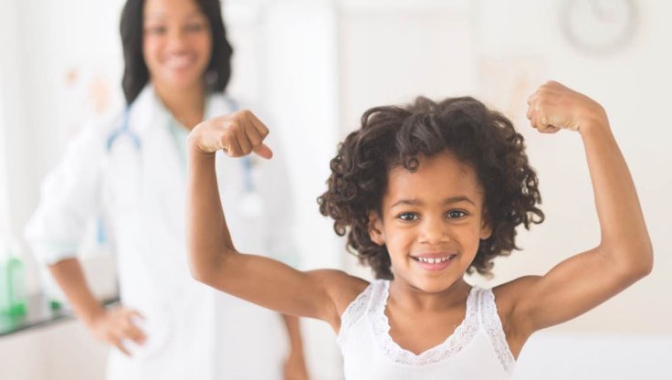 Young girl flexing her muscles with mom in the background. 