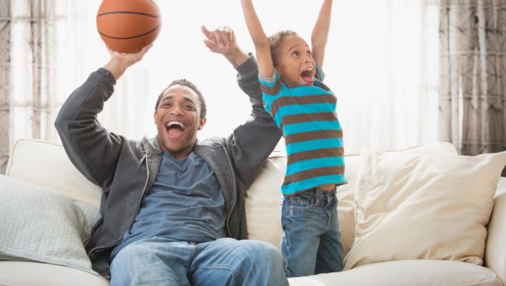 Father and son celebrating on a couch. 