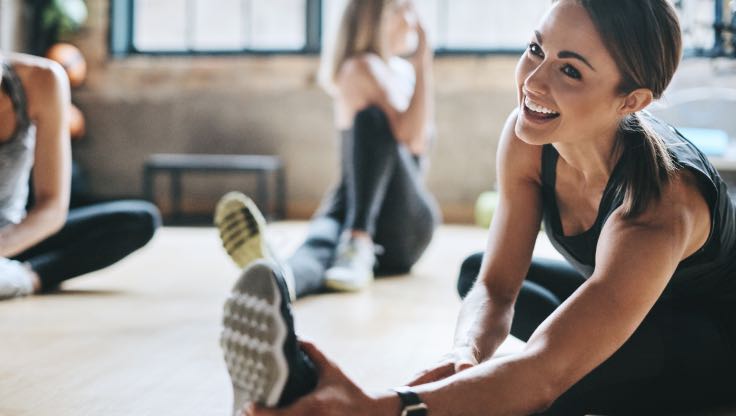 Woman smiling and doing a seated stretch