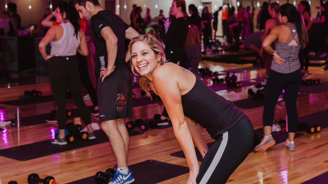 A women in a group fitness class smiling.