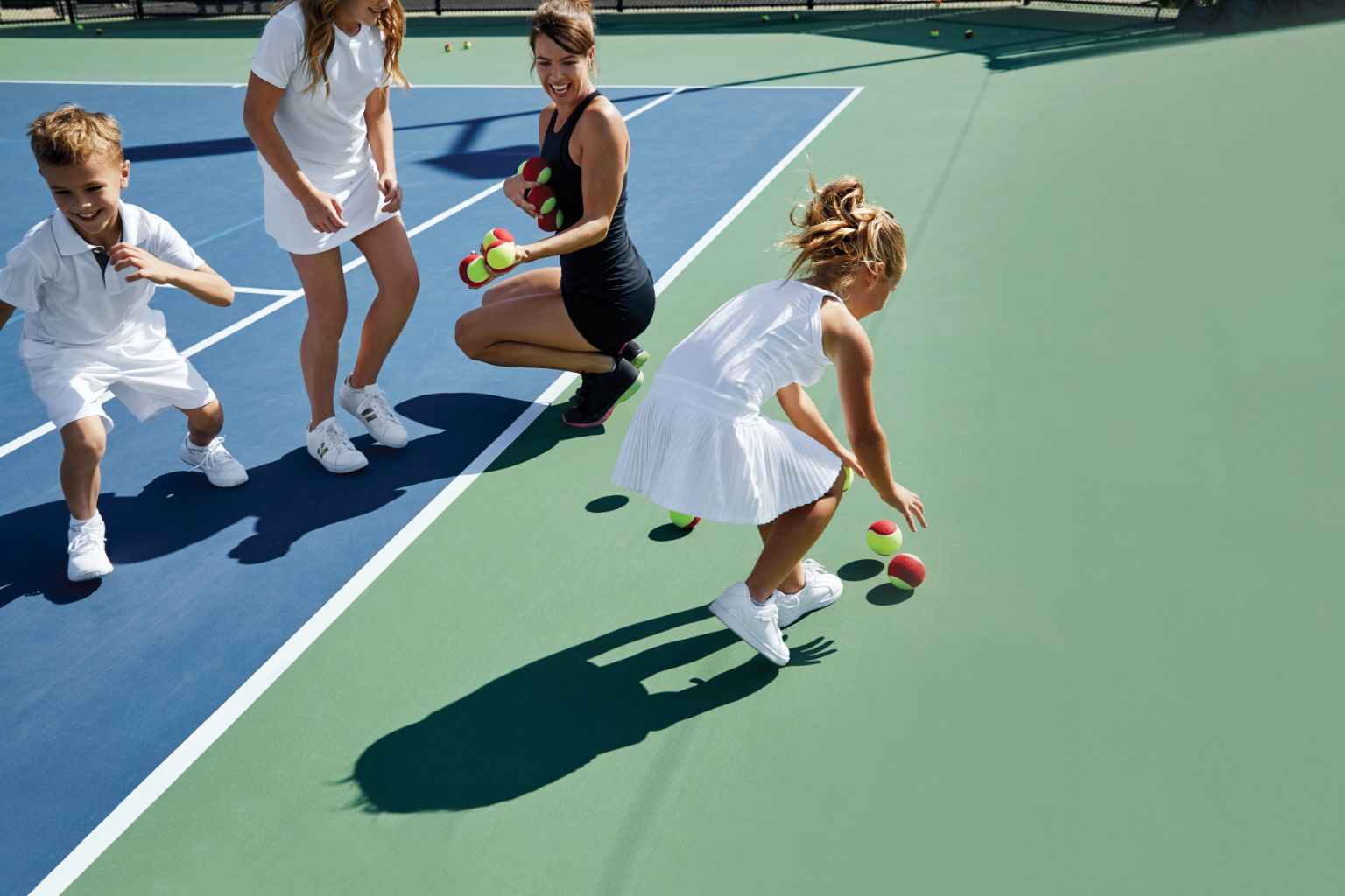 group of kids picking up tennis balls on a tennis court