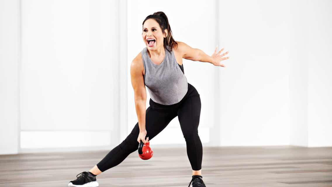 a woman taking a kettlebell komnbine class at home with Life Time Classes On Demand