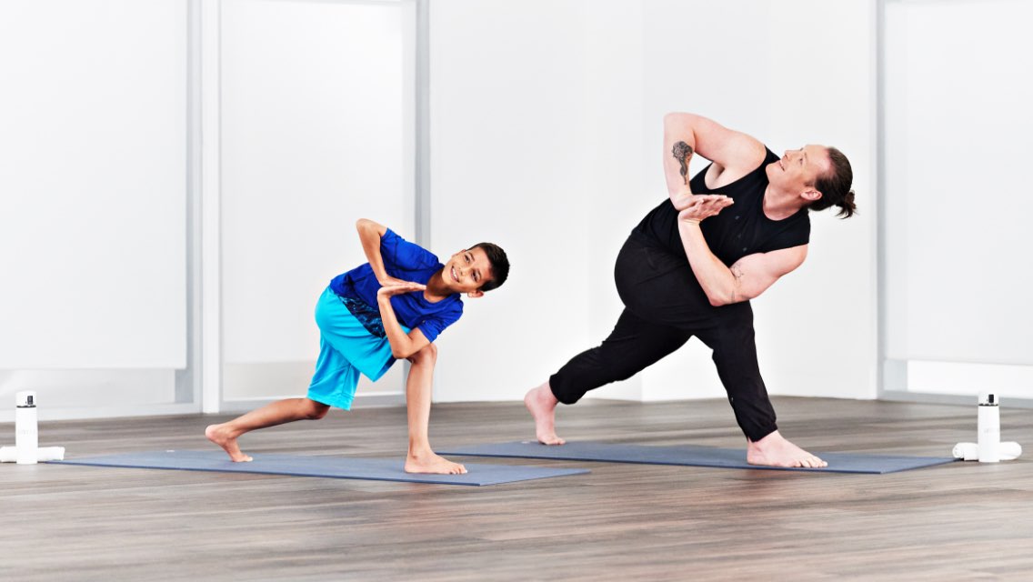 a man and a young boy performs a side twist yoga pose