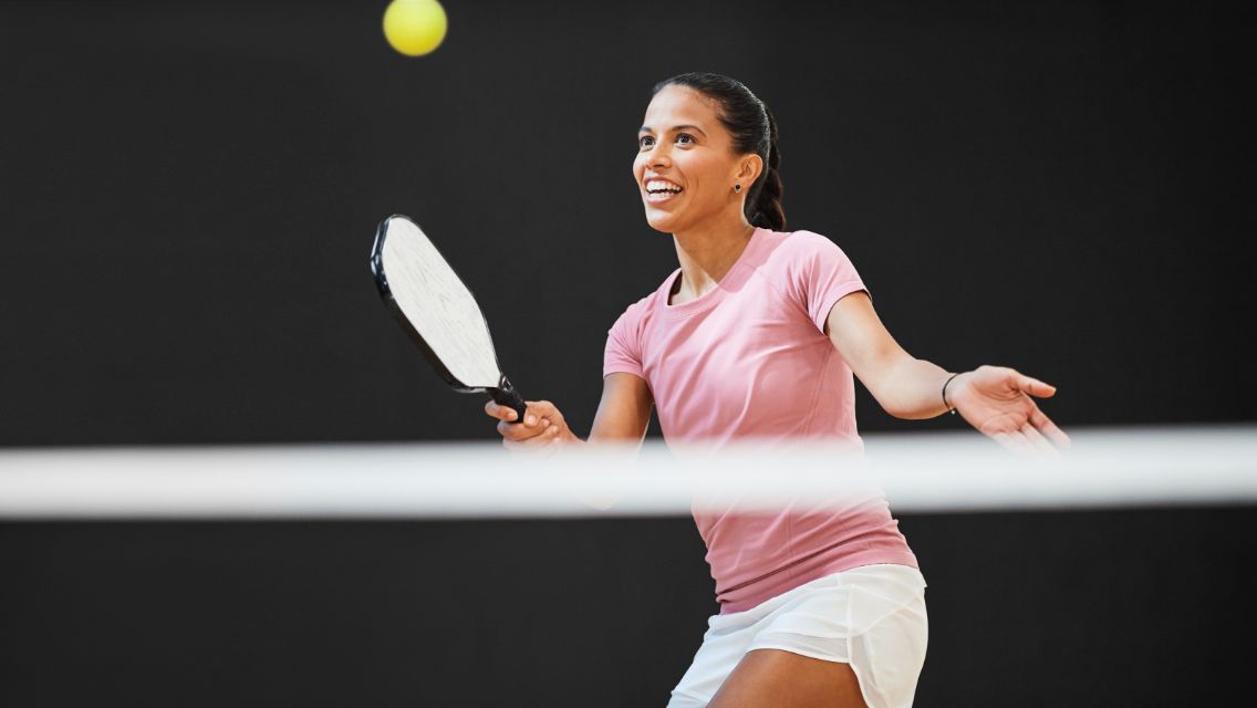 A woman hitting a pickleball with her racket