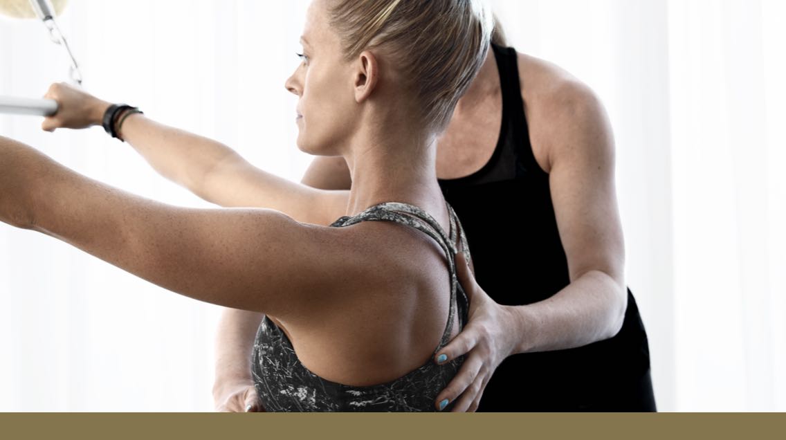 A Pilates instructor helping a student with her form