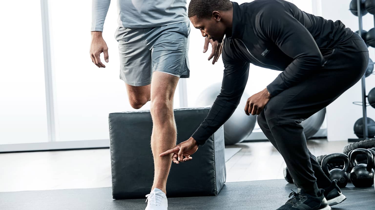  Life Time trainer helps his client with proper form during an exercise