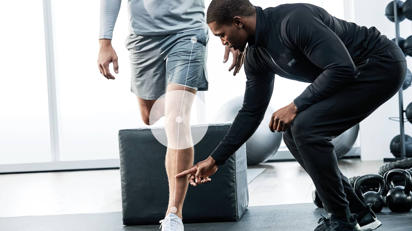 A Life Time trainer helps his client with proper form during an exercise