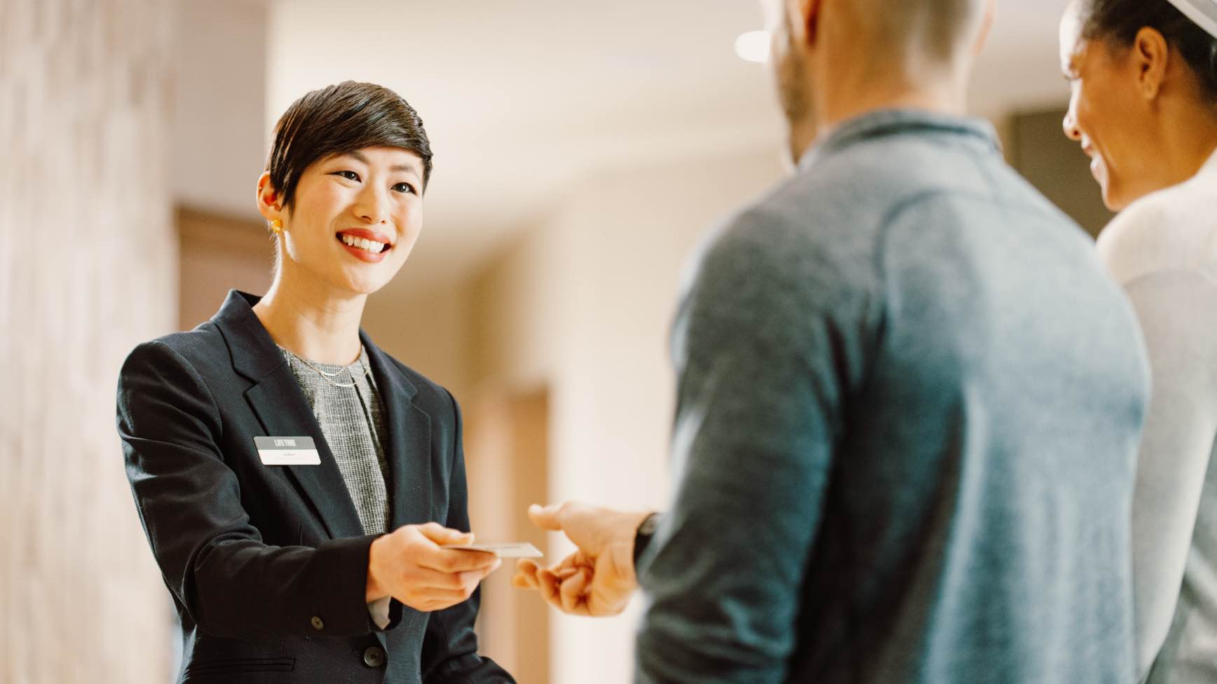 Image of woman handing a business card to a man.