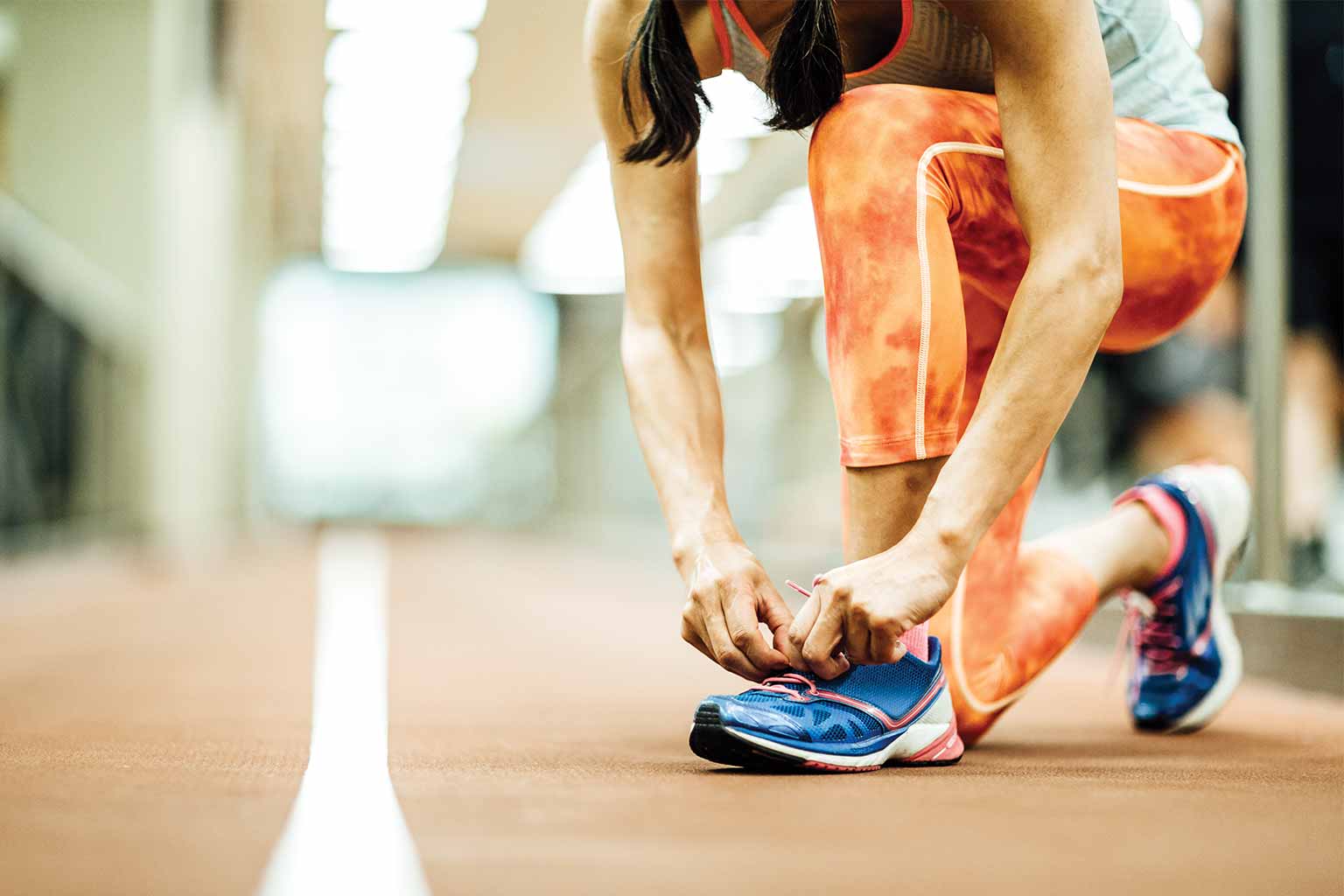 a young athletic man bending over tying his shoe