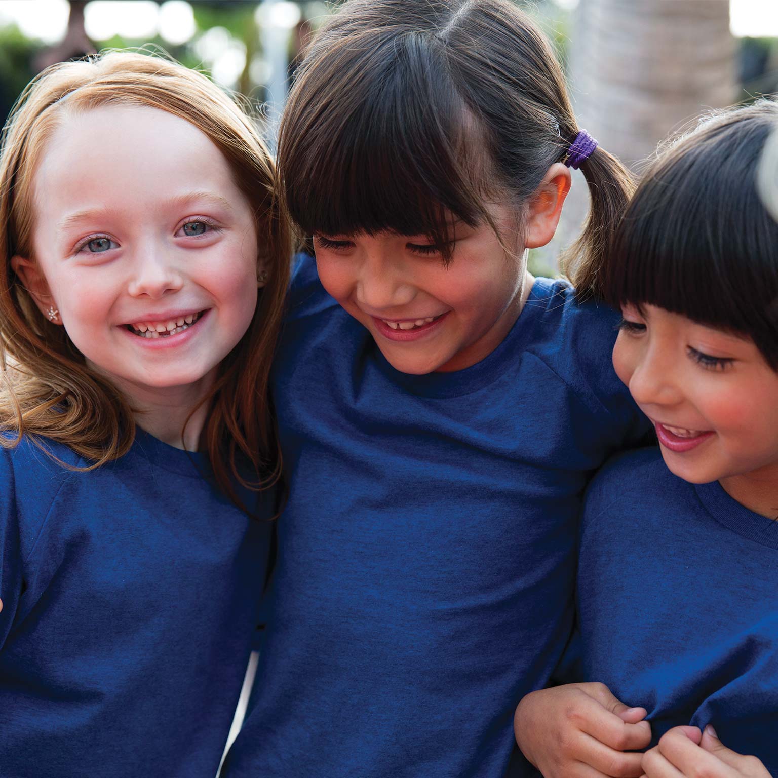 a group of girls wearing blue shirts and their arms around each others backs