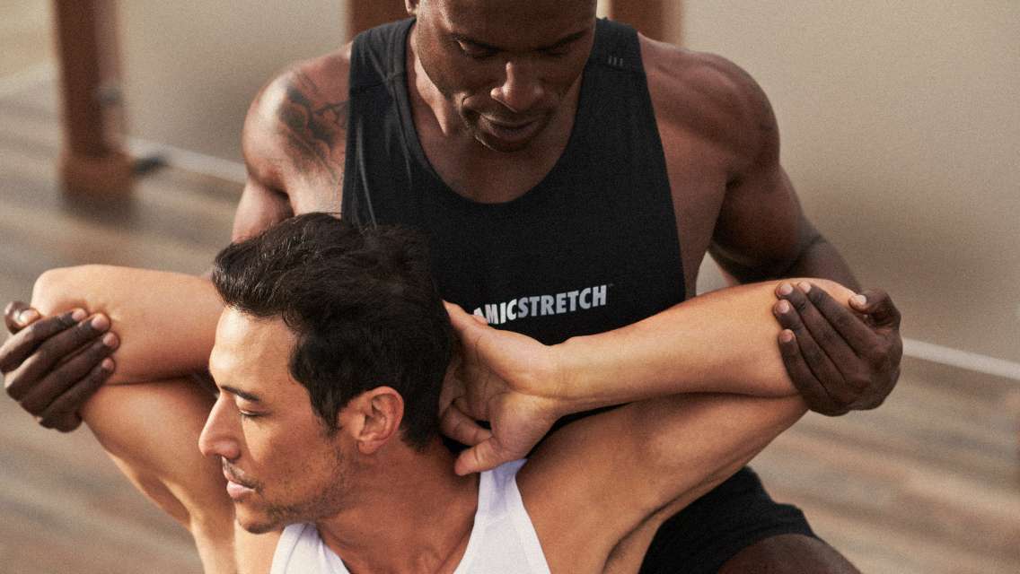 a trainer helping a man stretch ou his shoulders