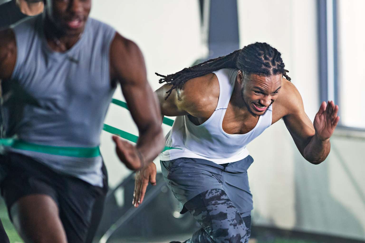 Man participating in a Gameface resistance drill on an indoor turf field.