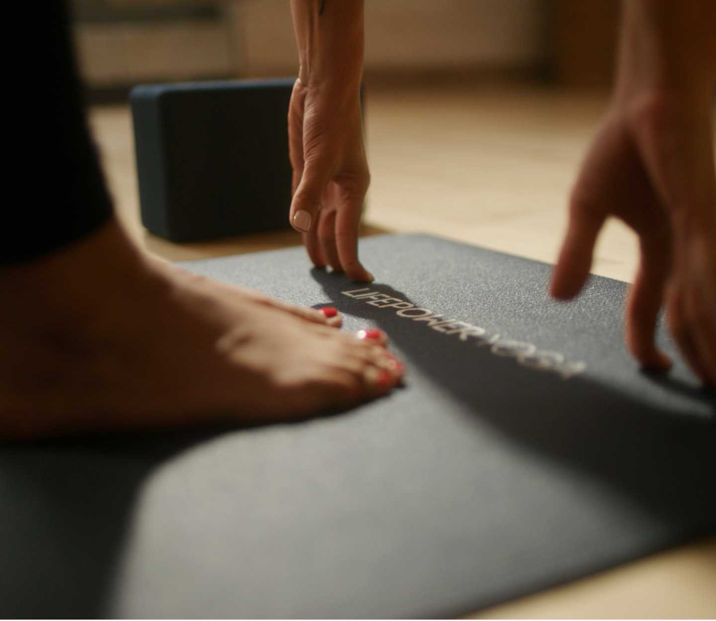 a foot and two hands touching a gray yoga mat