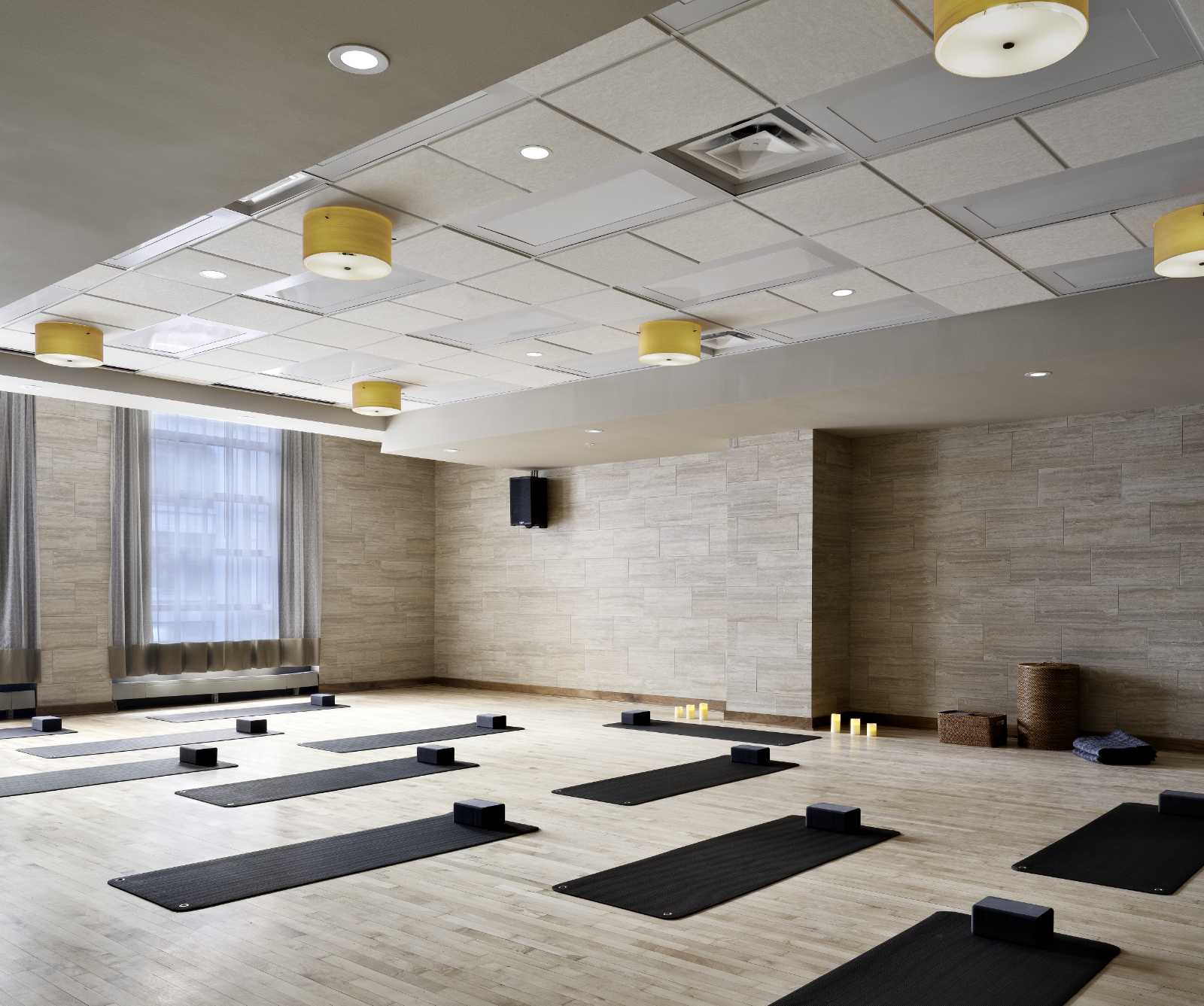 A bright studio classroom with yoga mats and yoga bricks laid out