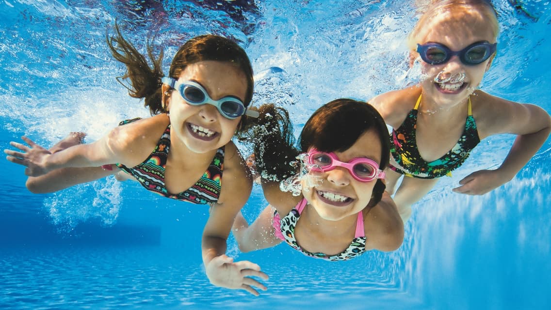 three girls swimming under water